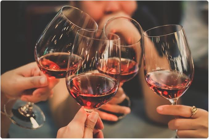 Four glasses of red wine raised together in a toast